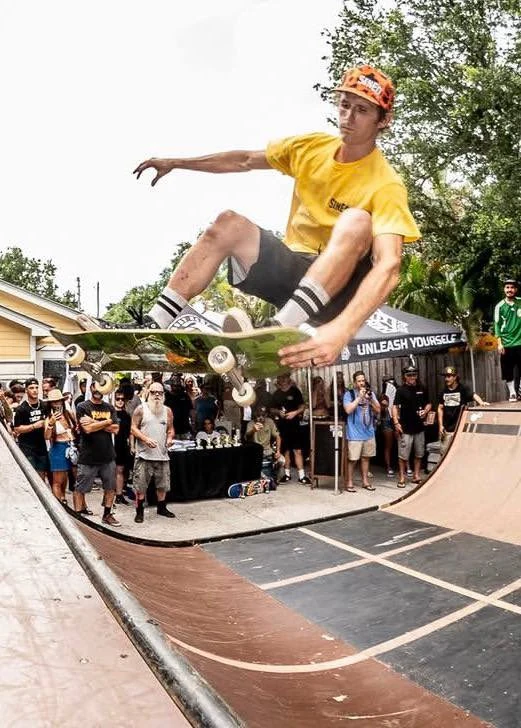 Skateboarder in a yellow shirt above a ramp and an Unleash Yourself banner