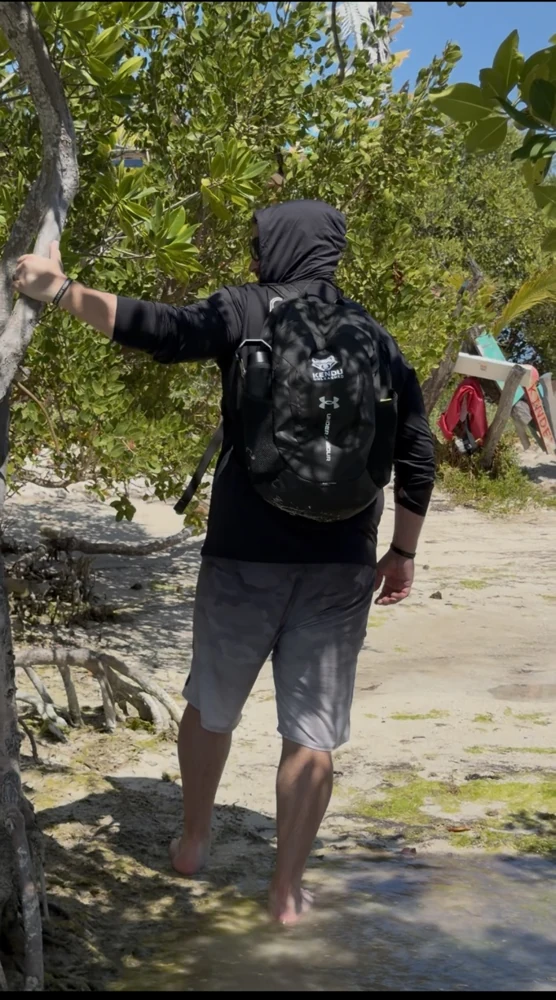 Person walking toward the beach with a Kendu Unleashed backpack